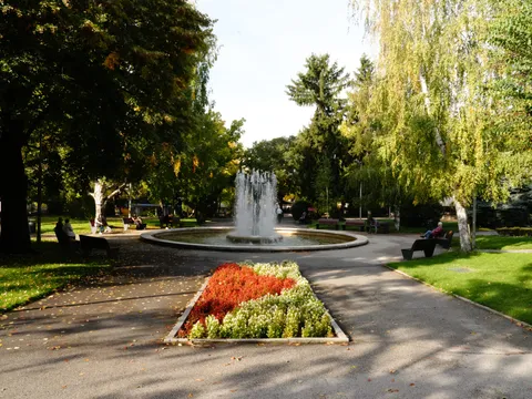 Алея с цветна леха, която води към фонтана в парка