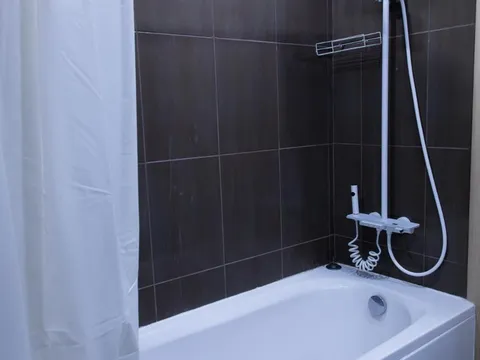 Баня с тъмни плочки, вана и душ със завеса