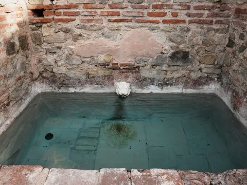 Квадратен басейн с минерална вода и малка лъвска глава в стената