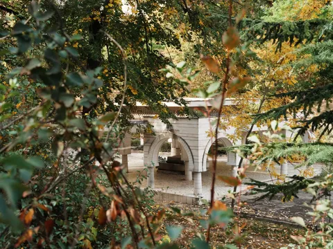 Бял павилион с арки, видян през есенни клони
