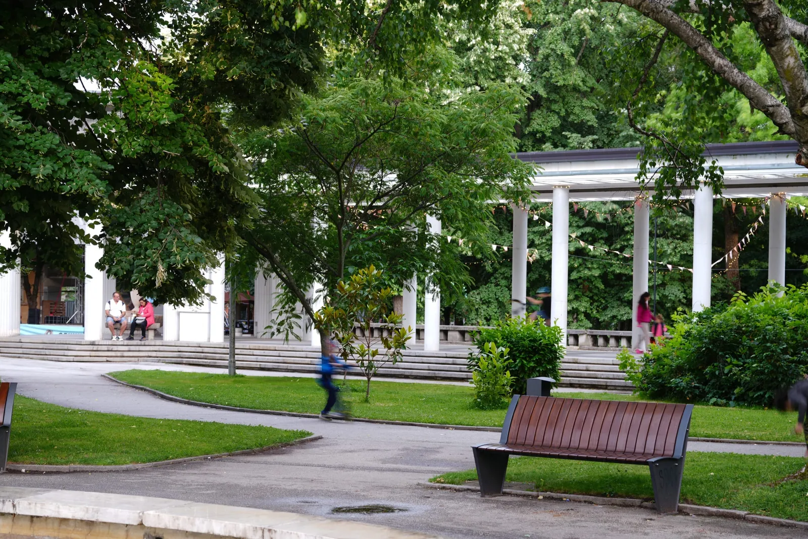 Бялата колонада в парка в Хисаря, пейка и зелени лехи пред нея