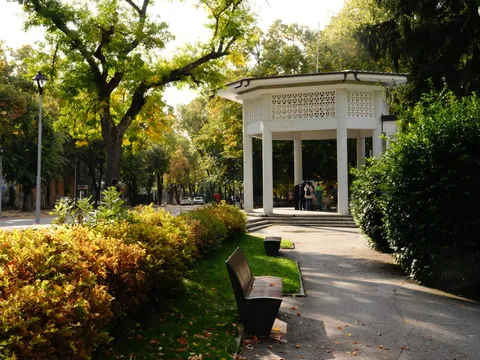 Бялата осмоъгълна беседка, пейки и есенни храсти край алеята