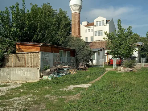 Минарето на джамията в Хисаря над ниска сграда и тревист двор