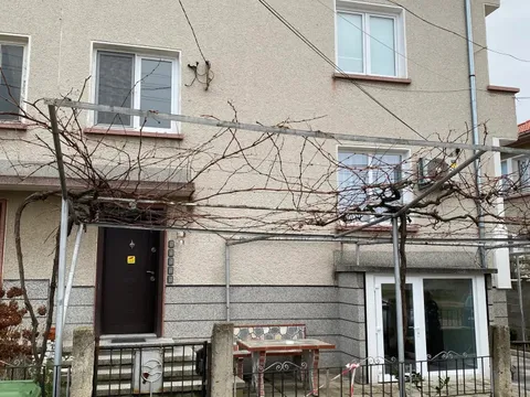 Триетажната къща за гости със светла фасада, лозница и малък двор пред входа