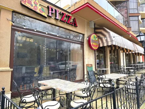 Фасадата на Пицария Тоскана с надпис „Pizza“ и маси на тротоара