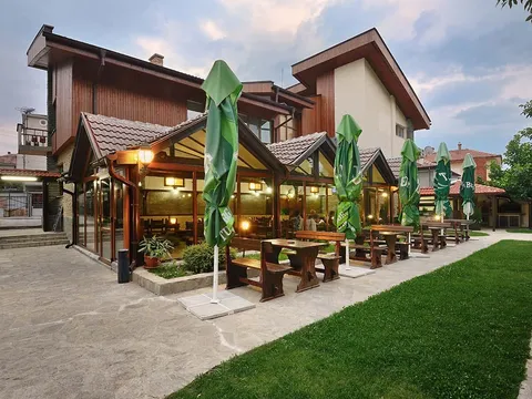 Пътека, морава и маси под чадъри пред сградата на ресторанта