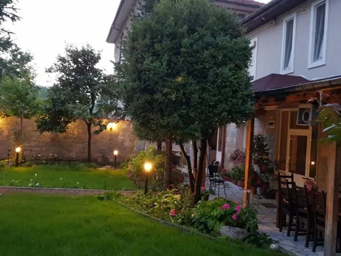 Градината с осветление вечер и покрит кът за хранене