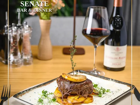 Основно ястие с месо, чаша червено вино и бутилка на маса в Senate Bar & Dinner