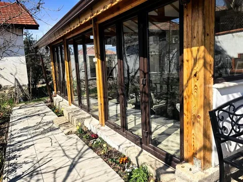 Остъклена веранда с дървени колони и пътека в градината