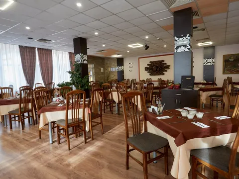 Ресторант с дървени столове и маси с бели и кафяви покривки