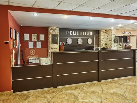 Рецепция с тъмен плот, мраморен под и картини по стените