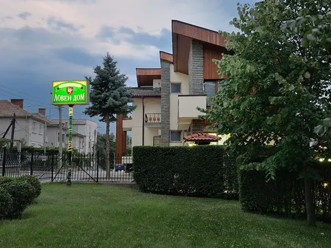 Сградата на „Ловен дом“ с дървени фронтони, морава и храсти