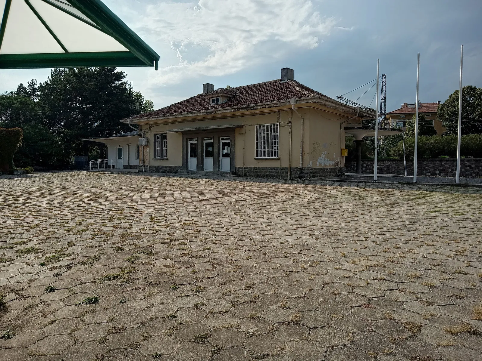 Едноетажната жълта сграда на ЖП гара Хисаря и павираният площад пред нея
