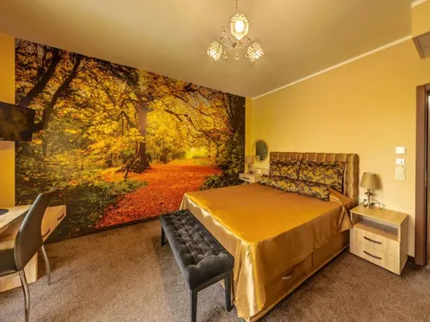 Стая във Victoriya's House с фототапет на есенна гора и златисто легло
