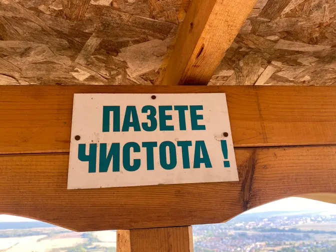 Табела „Пазете чистота!“ под покрива на беседката с гледка към града