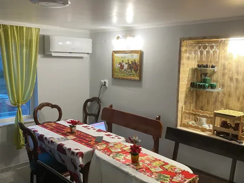 Трапезария с дълга маса с покривка, дървени столове и пейка