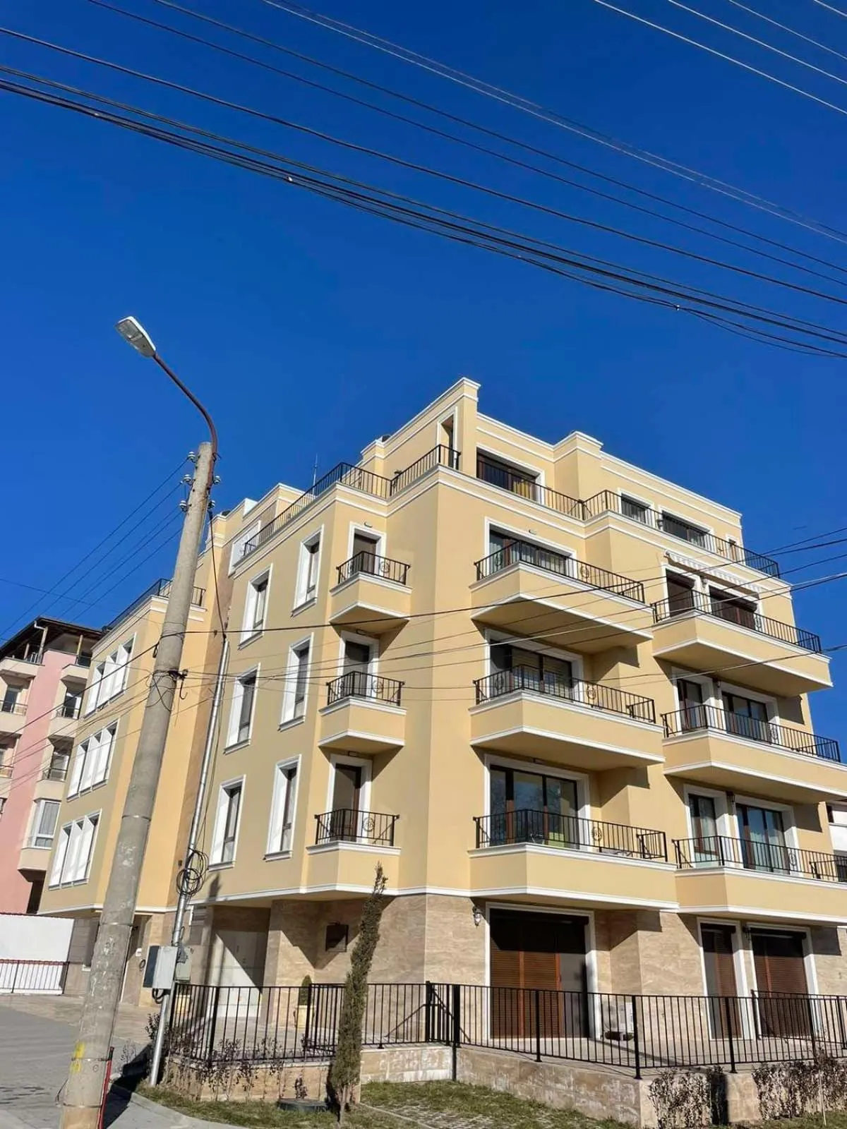 Пететажна жълта сграда с балкони на „Вила Витоша“ под синьо небе